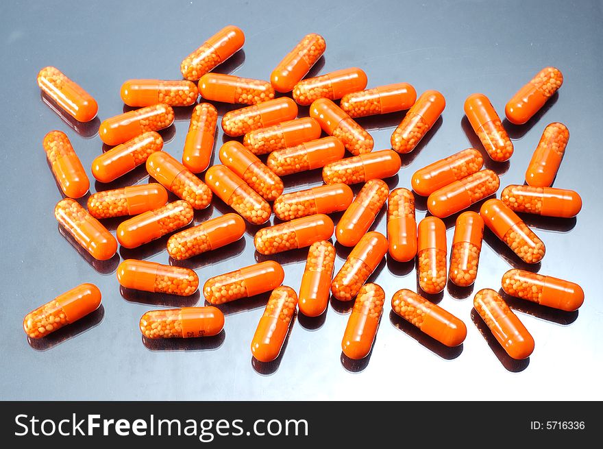 Drugs in orange capsules on grey background. Drugs in orange capsules on grey background