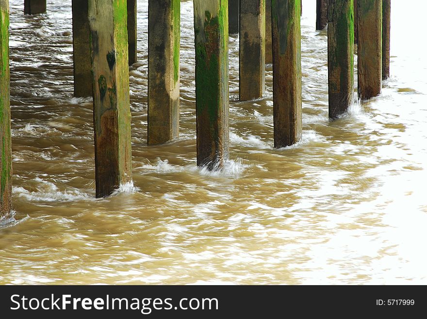 Shot showing a river lapping pier legs. Shot showing a river lapping pier legs
