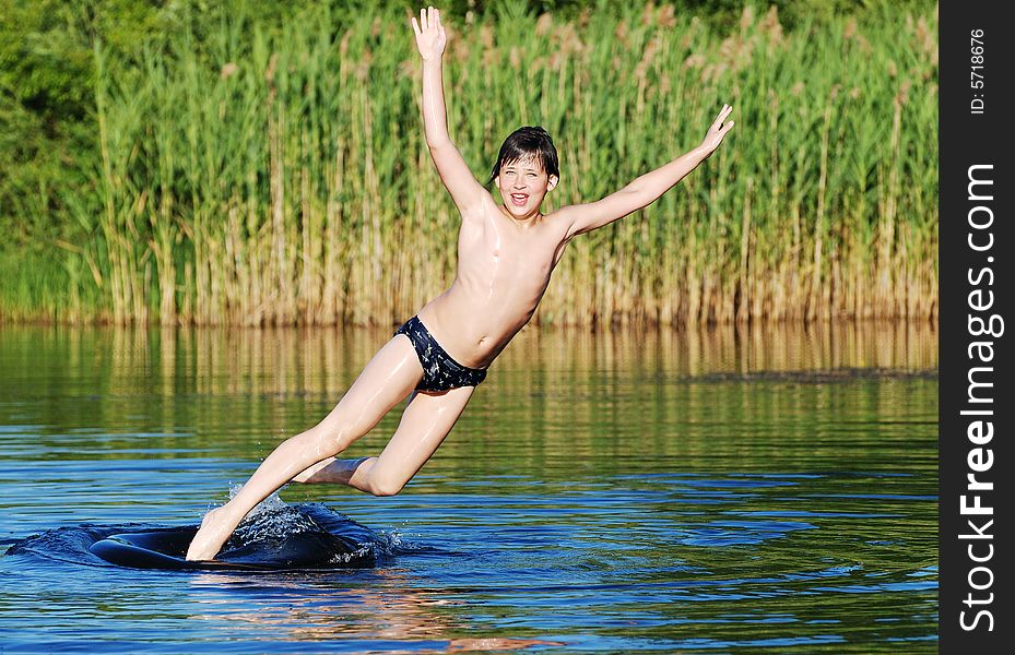 The boy is falling down off the tube to the lake water in a graceful way. The boy is falling down off the tube to the lake water in a graceful way.