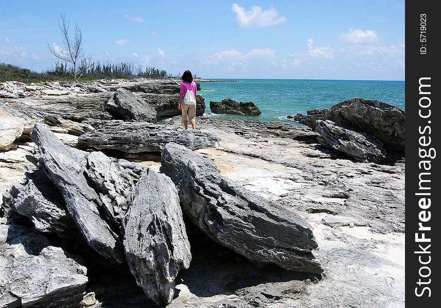 The girl walking along rocky hostile beach in Freeport on Grand Bahama Island, The Bahamas. The girl walking along rocky hostile beach in Freeport on Grand Bahama Island, The Bahamas.