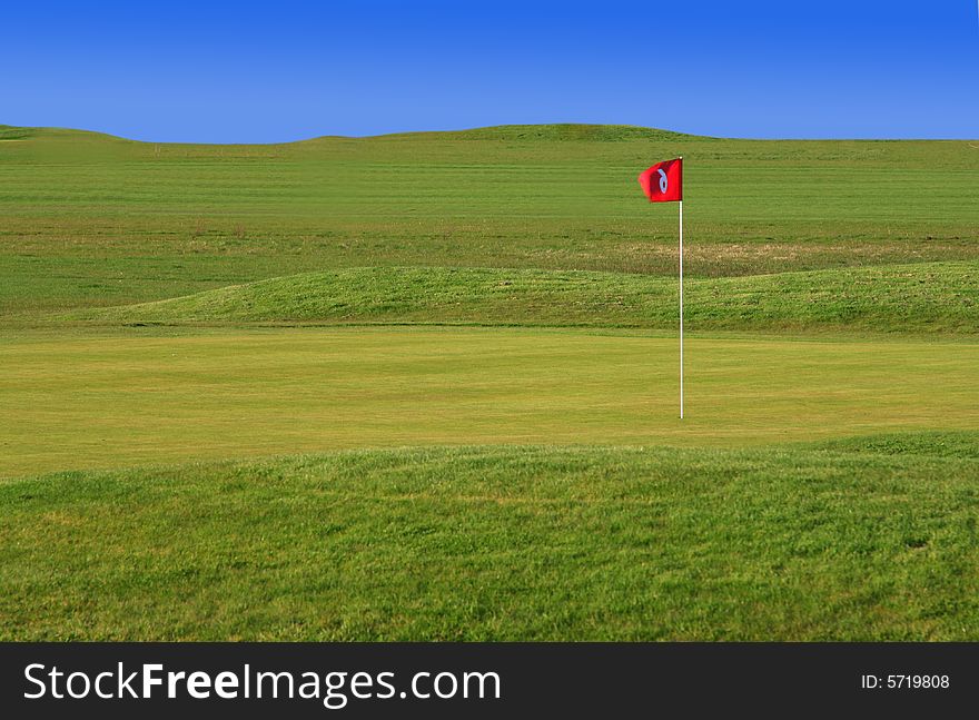 Green golf court with red flag
