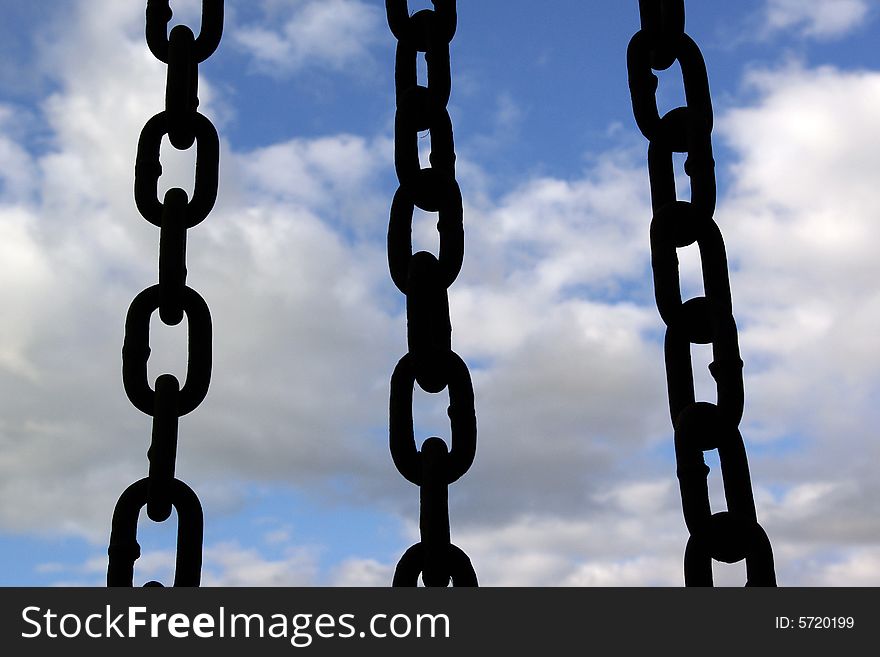 Three black chain hang down on sky background