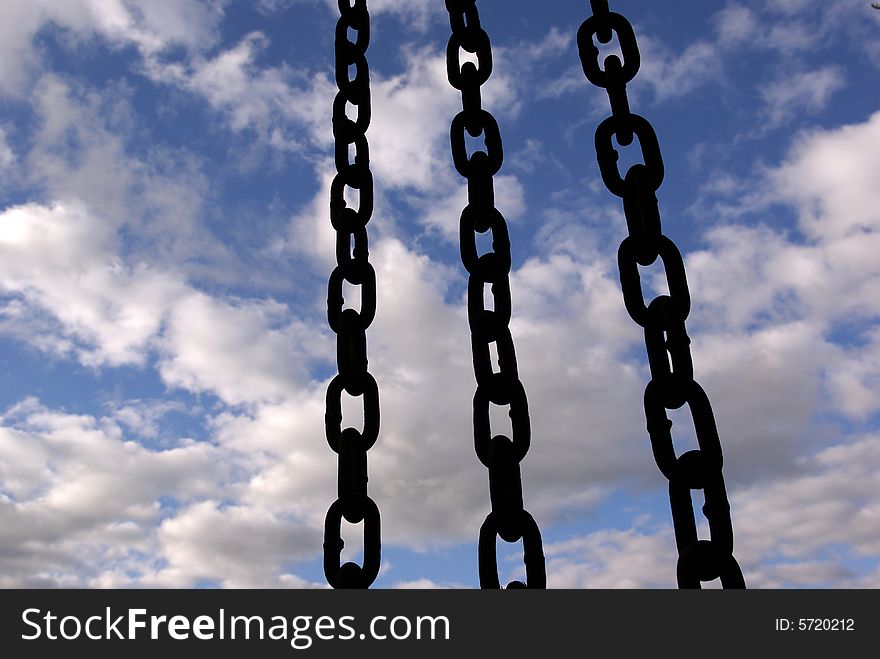 Three black chain hang down on sky background