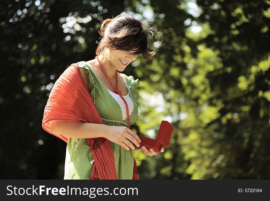 Young happy woman smiling outdoors with a jewelry box in her hands. Young happy woman smiling outdoors with a jewelry box in her hands