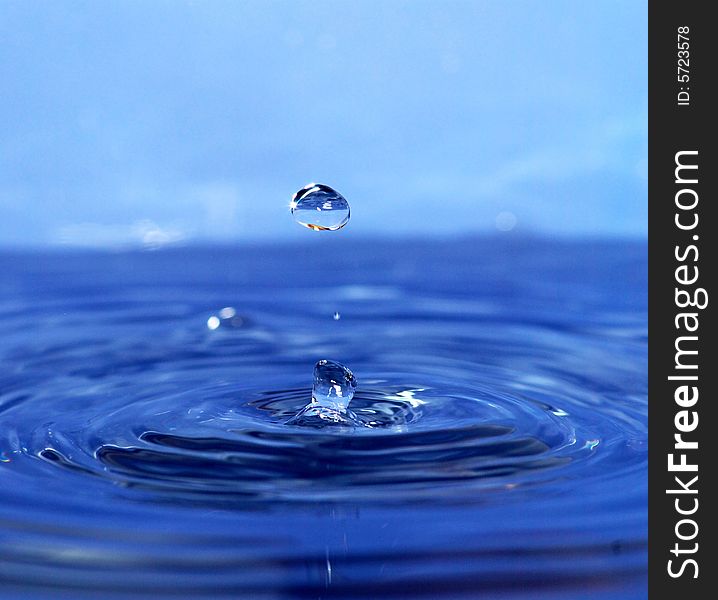 The round transparent drop of water falls downward. The round transparent drop of water falls downward