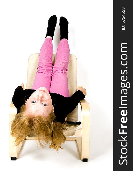 Little girl is hanging upside down on a chair