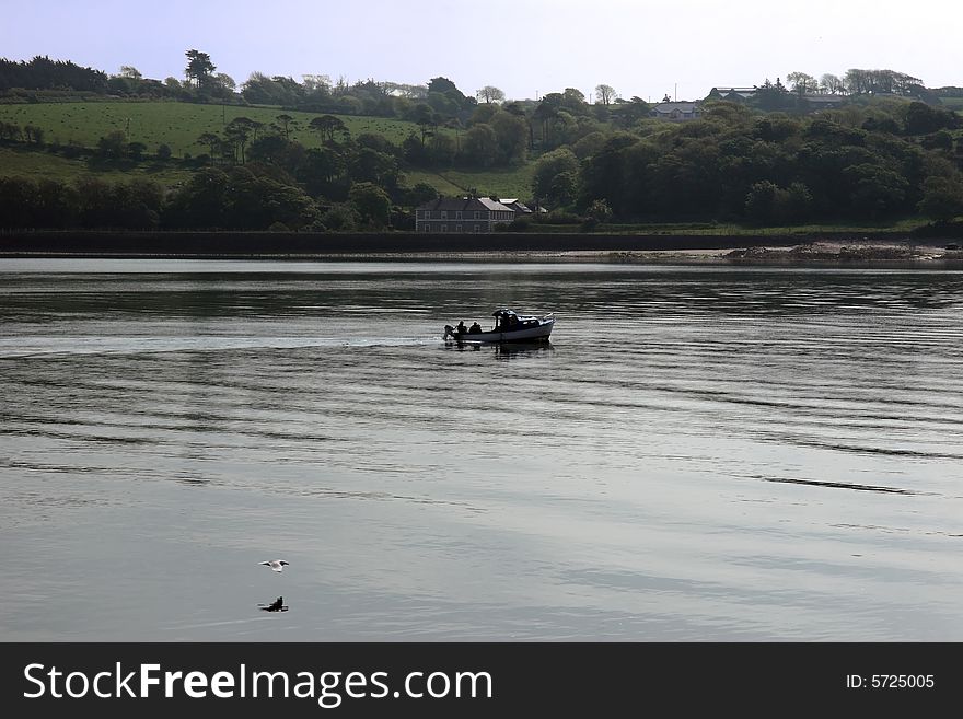 People fishing from a boat on the river blackwater in ireland with a seagull flying by. People fishing from a boat on the river blackwater in ireland with a seagull flying by