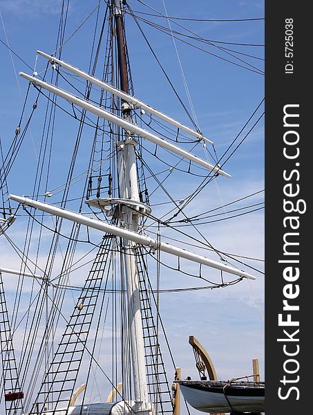 A white ship mast and life boat against a bright blue sky