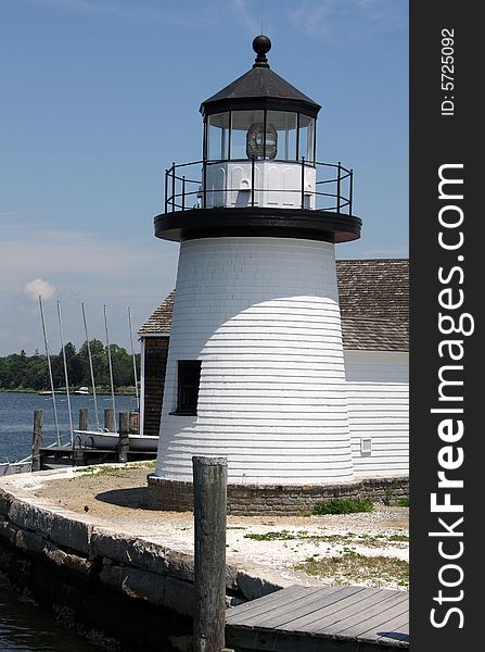 A white and black lighthouse on the edge of a dock