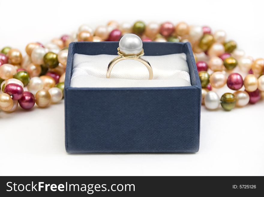 A golden ring with pearl on colorful beads background. A golden ring with pearl on colorful beads background.