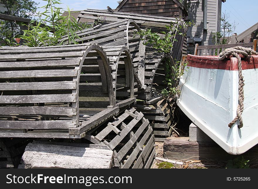 A stack of wooden lobster traps next to a rowboat on the dock. A stack of wooden lobster traps next to a rowboat on the dock