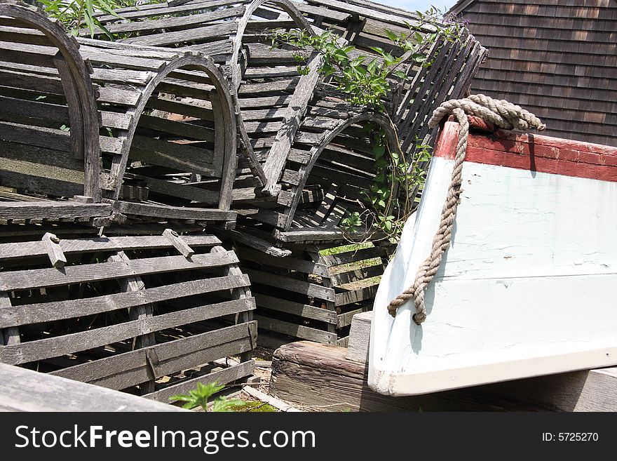 A stack of wooden lobster traps next to a rowboat on the dock. A stack of wooden lobster traps next to a rowboat on the dock