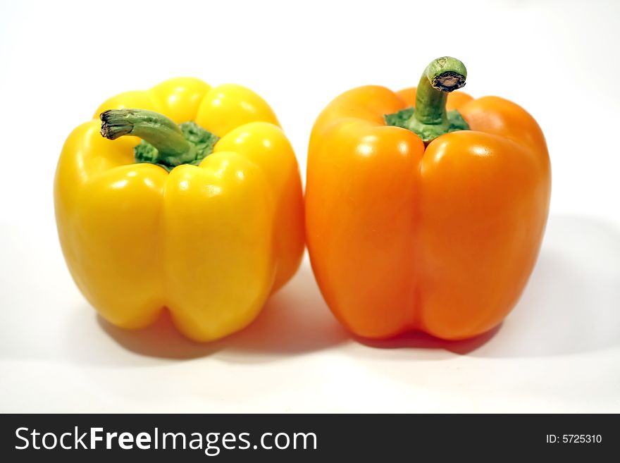 Two bell peppers, one yellow, another orange, isolated on a white background. Two bell peppers, one yellow, another orange, isolated on a white background.