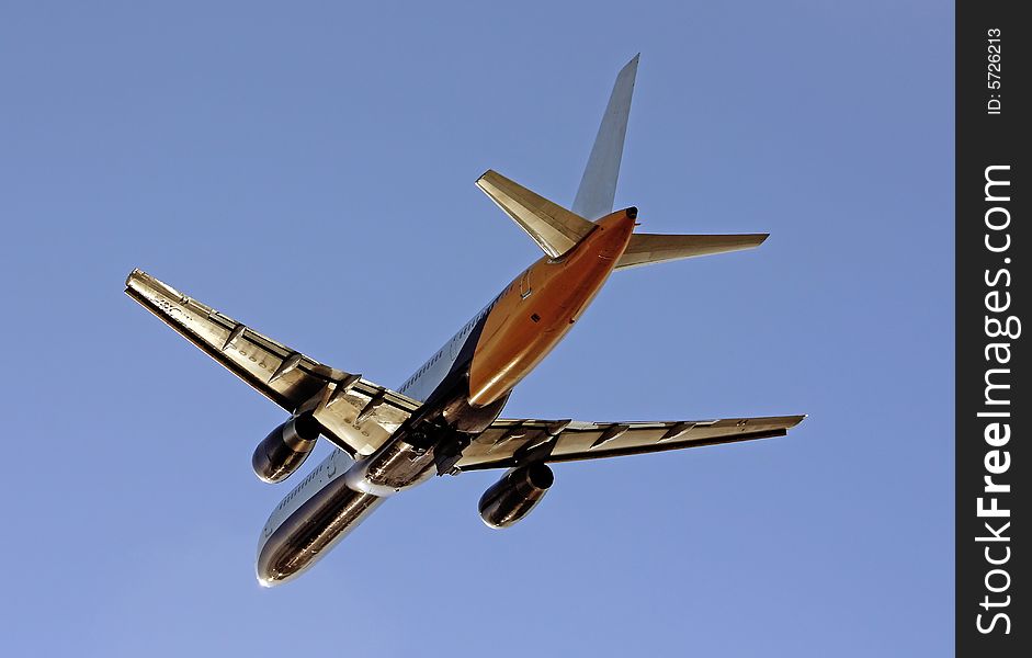 View of a commercial plane departing from the airport, isolated on a blue sky. View of a commercial plane departing from the airport, isolated on a blue sky