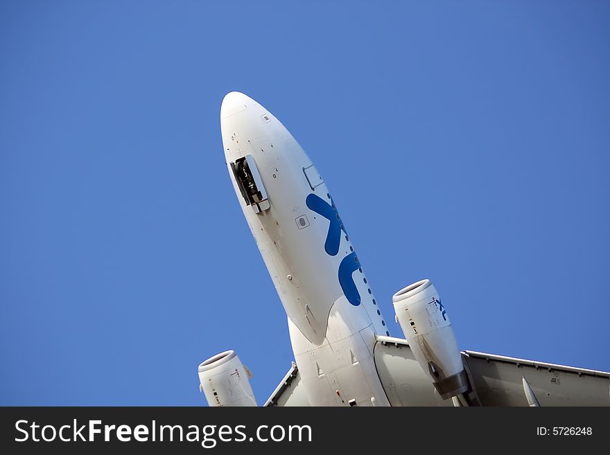 Half view below of a commercial plane arriving at the airport, with a blue sky. Half view below of a commercial plane arriving at the airport, with a blue sky.