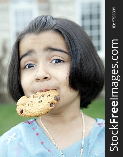 East indian little girl eating a chocolate chip cookie. East indian little girl eating a chocolate chip cookie