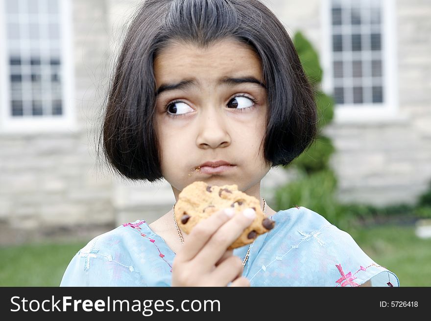 East indian little girl eating a chocolate chip cookie. East indian little girl eating a chocolate chip cookie