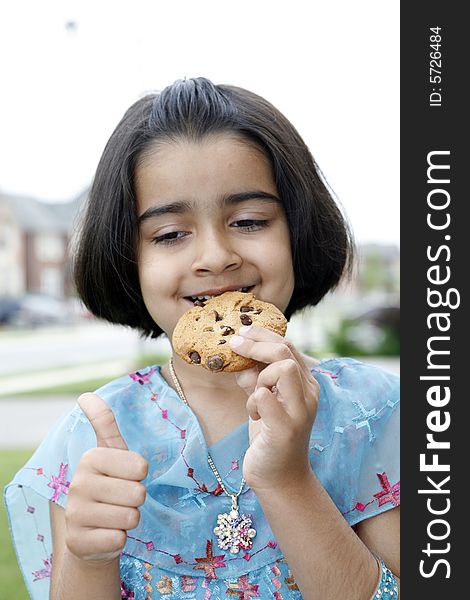 East indian little girl eating a chocolate chip cookie. East indian little girl eating a chocolate chip cookie