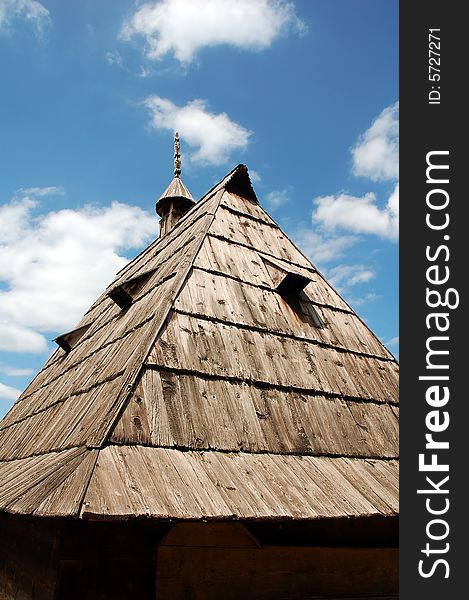 An old wooden roof on a primitive country house with a wooden with a decorative chimney. An old wooden roof on a primitive country house with a wooden with a decorative chimney