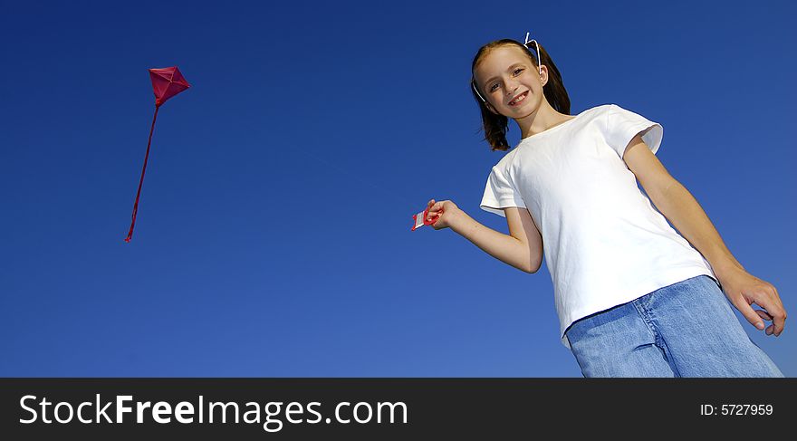 Girl flying a kite in a park with blue sky