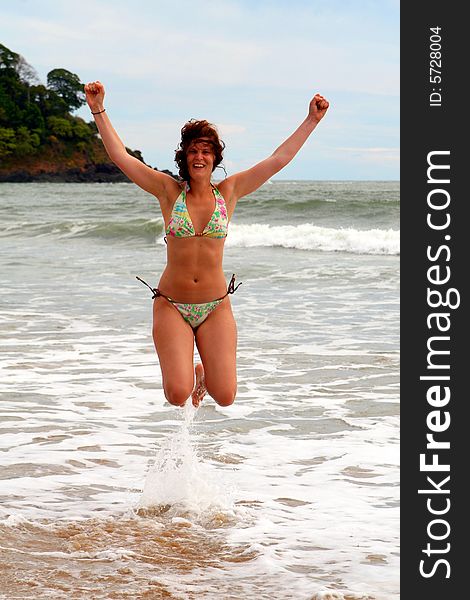 Young woman is jumping at the beach expressing joy and freedom. Ideal vacation / summer shot. Young woman is jumping at the beach expressing joy and freedom. Ideal vacation / summer shot.