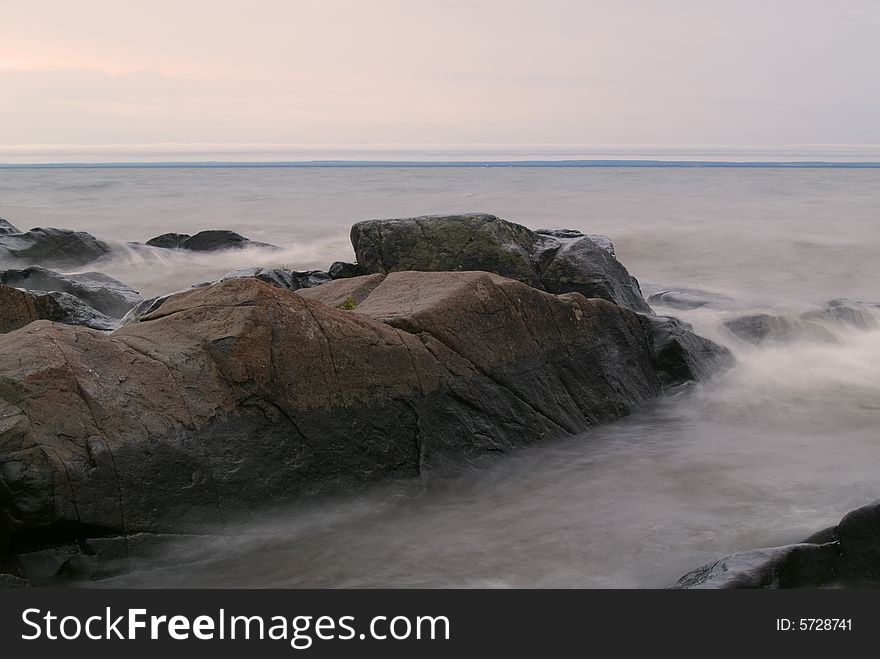 Stones in stormy and misty grey water on Lake Superior. Stones in stormy and misty grey water on Lake Superior.