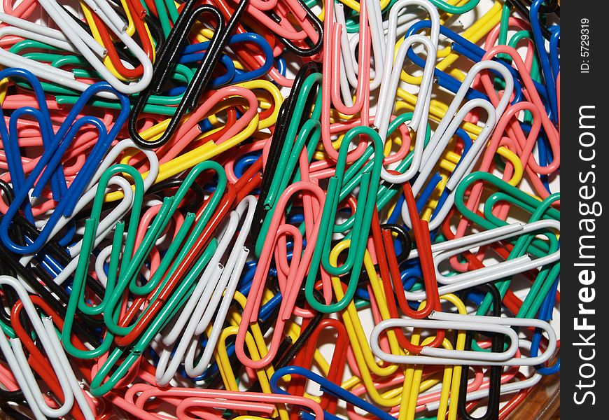 Layer of Coloured Paperclips on a wooden desk. Layer of Coloured Paperclips on a wooden desk