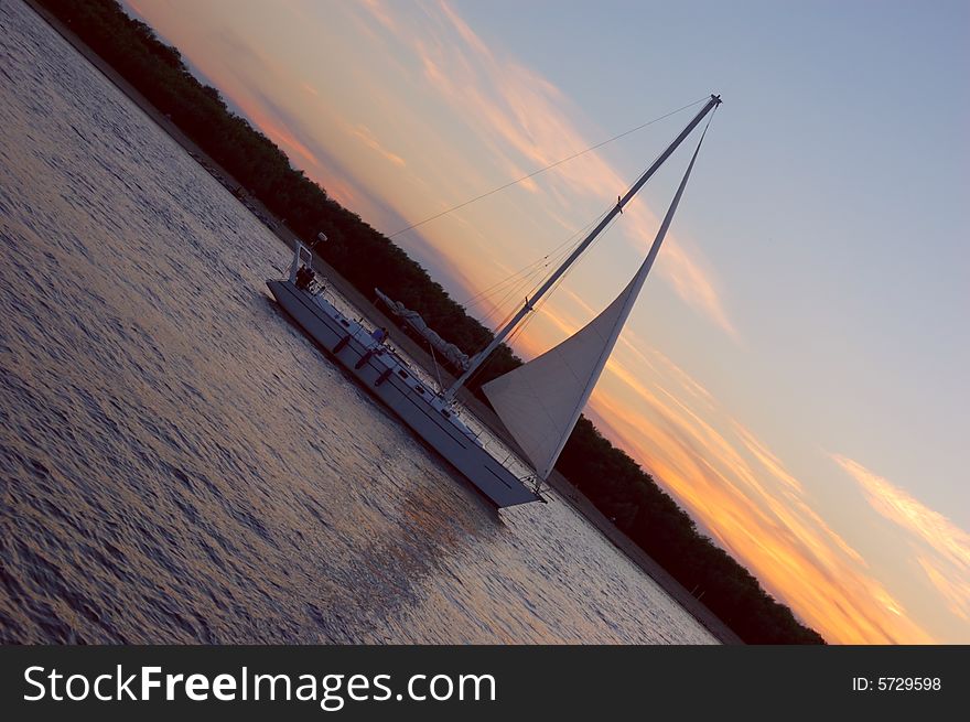 Yacht sailing Volga-river against sunset