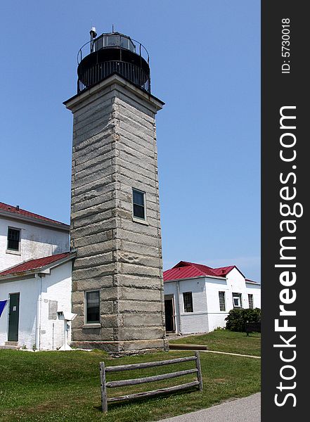 A gray concrete lighthouse connected to white buildings