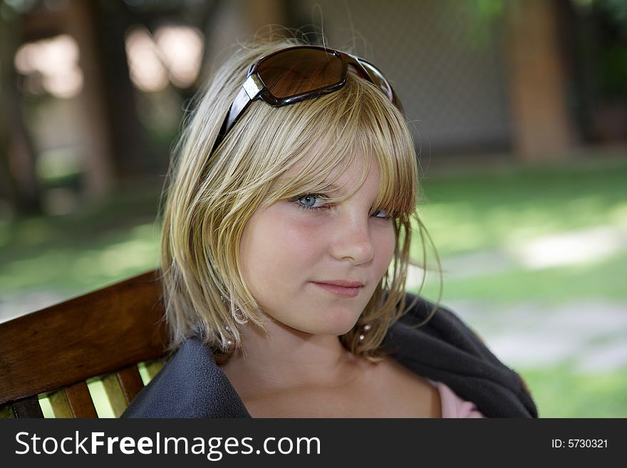 Young pretty girl sitting in shade outdoors with sunglasses on her head. Young pretty girl sitting in shade outdoors with sunglasses on her head