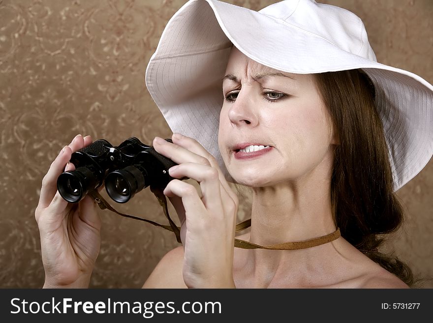 Young Woman with Sunglasses and a Floppy White Hat Looking through the Wrong End of Binoculars. Young Woman with Sunglasses and a Floppy White Hat Looking through the Wrong End of Binoculars