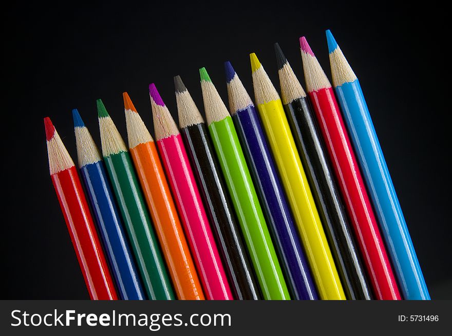 Colored pencil crayons slanted on black background. Colored pencil crayons slanted on black background
