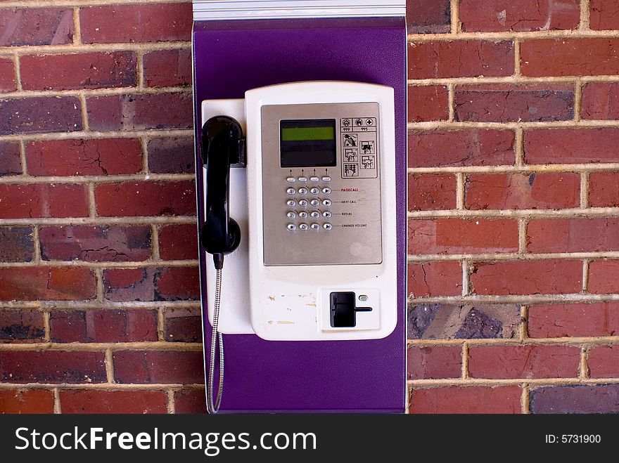 Traditional coin telephone set hanging on red brick wall. Traditional coin telephone set hanging on red brick wall