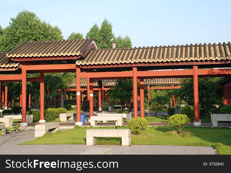 The long roofed corridor with red coloumns in a Chinese ancient garden,stone stools. The long roofed corridor with red coloumns in a Chinese ancient garden,stone stools.