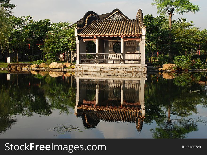 A Chinese traditional styled pavilion house by the pond in an ancient garden. A Chinese traditional styled pavilion house by the pond in an ancient garden.