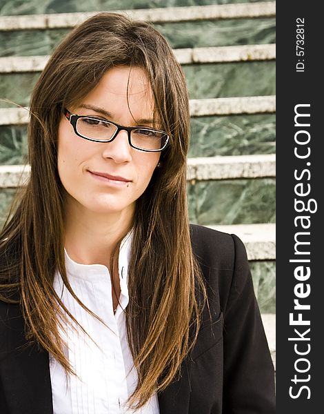 Young businesswoman staring at camera, marble stairs as background.