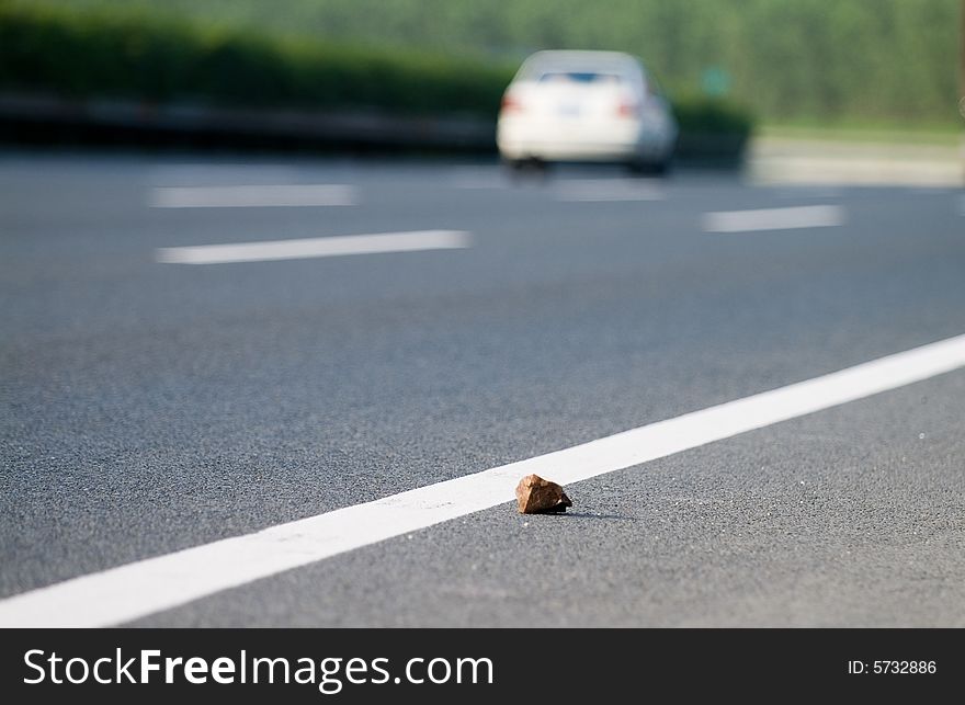 Stone fallen on the expressway makes latent danger to the passing vehicles.