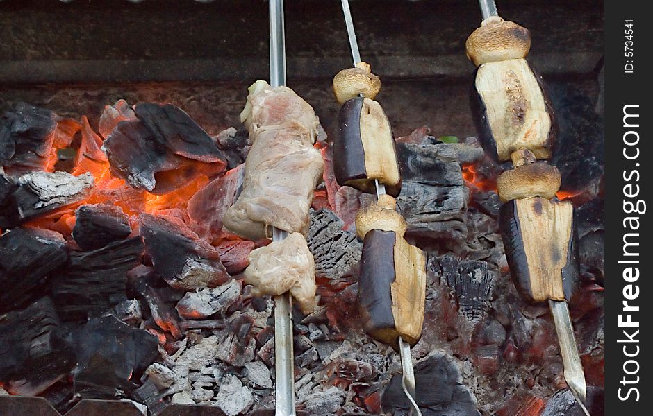 Meat and vegetable shish-kebab on skewers over red-hot coals