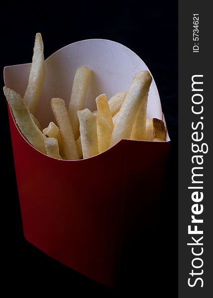 A box of french fries against a black background
