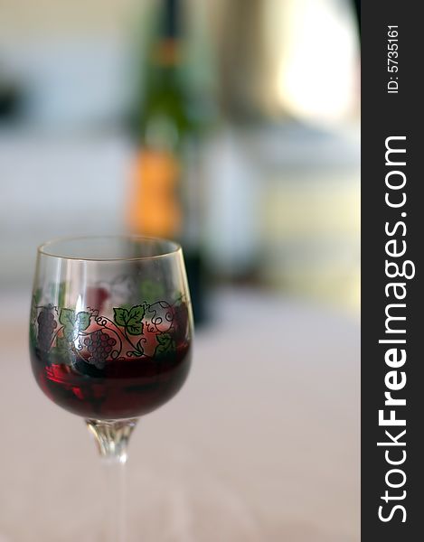 Glass with wine and wine bottle in background. Glass with wine and wine bottle in background