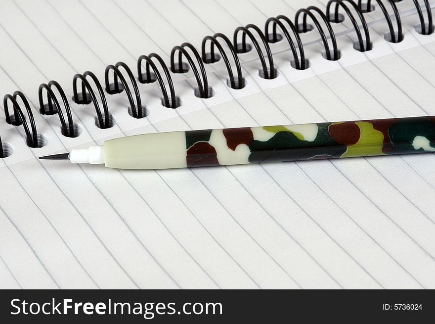 A camouflaged military styled pencil on a ring binder, photographed in a studio. A camouflaged military styled pencil on a ring binder, photographed in a studio.