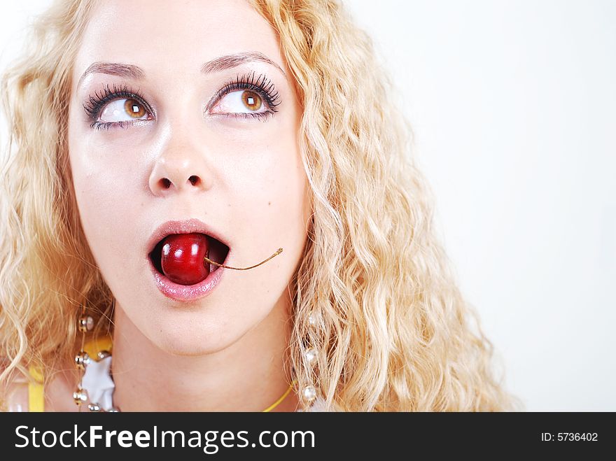 Beauty young woman with opened eyes and red cherry in mouth