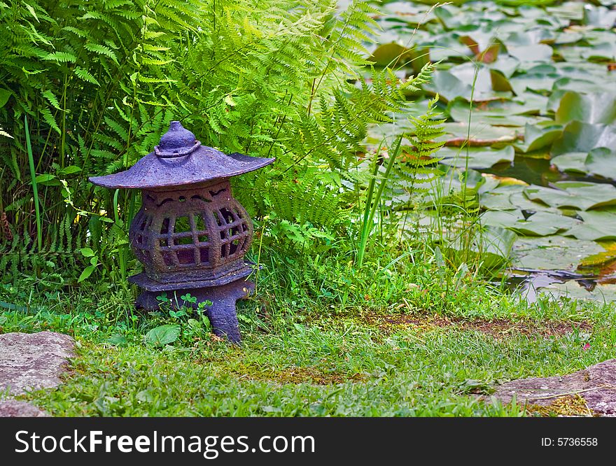 View of Japanese lantern in stroll garden near pond. View of Japanese lantern in stroll garden near pond