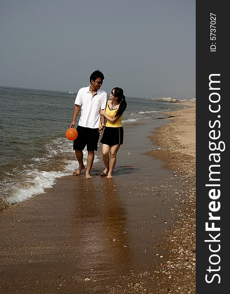 A young couple  holding hands walking on the beach