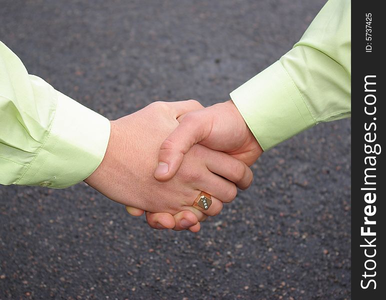 Men are shaking hands on a grey background.