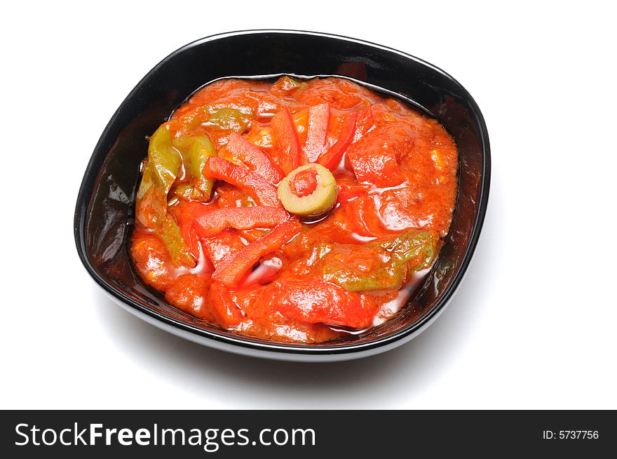 Cooked peppers with sauce in black dish isolated on white