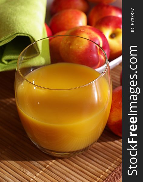 A glass of juice and nectarine on the table