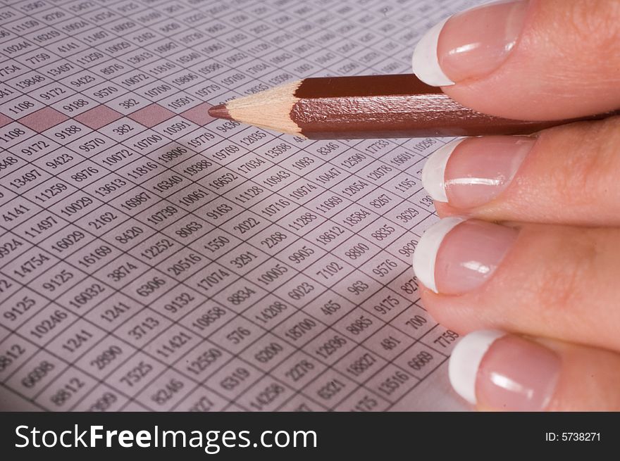 Pencil in fingers at table with figures. Pencil in fingers at table with figures