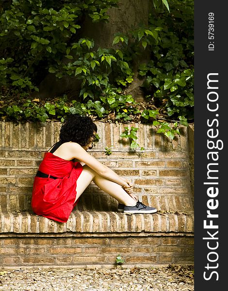 Red dress woman in brick bench.