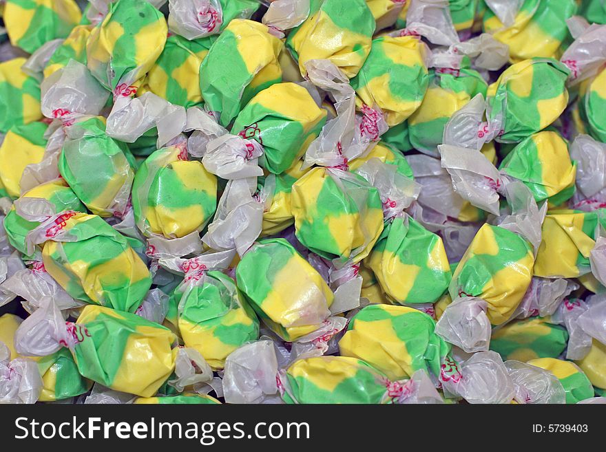 Lots of colorful green and yellow salt water taffy candies. Lots of colorful green and yellow salt water taffy candies